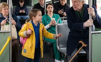 You can sit in my seat — said the little girl to the trembling old man; his bodyguards were watching him. The morning Emily Torres rode Route 78 by herself for the first time, she was seven years old and trying very hard to look braver than she felt. The bus smelled like rain-soaked coats, paper coffee cups, and the cold metal rail everyone grabbed when the driver braked too sharply. Emily sat in the second row by the window with her pink backpack hugged against her chest. Her yellow raincoat was too small in the shoulders, but her mother had said it would have to last until spring. Near the pocket, there was a patch Sarah Torres had sewn on three different times. The thread scratched Emily’s wrist whenever she moved, and every scratch reminded her of her mother sitting under the weak kitchen light, bending over that little sleeve after a double shift. Emily did not know the word “exhausted” yet. She only knew the way her mother sometimes smiled while looking like she might cry. That morning had begun before the sun was fully up. Sarah had woken Emily in the dark apartment, brushed her hair gently, packed her school folder, and wrapped a piece of cornbread in a napkin because breakfast had to be eaten on the way. The apartment was quiet except for the hum of the refrigerator and the click of Sarah’s work shoes on the kitchen floor. On the counter, half-hidden under a grocery receipt, was a red electric notice. Emily had seen it. Sarah had seen Emily seeing it. Neither of them said a word. Children notice what adults try to fold away. At 6:18 a.m., Sarah knelt beside Emily at the bus stop and held both of her shoulders. Not hard. Just firm enough to make sure the child understood every word. “You get off right after the pedestrian bridge, baby,” Sarah said. “Count five stops. Don’t talk to anyone. Sit close to the driver.” Emily nodded. “Yes, Mom.” “Five stops.” “I know.” “And if anything feels wrong?” “Tell the driver.” Sarah swallowed, then smoothed the patched sleeve of the yellow raincoat. Her fingers lingered there a second too long. Emily had never ridden to school alone before, but the breakfast shift at the market started early, and Sarah could not miss another hour. Rent was due Friday. The electric bill was not the only red paper in her purse. There are mornings when poor mothers do not choose between good and bad. They choose between bad and worse, then pray their children never learn the difference. Sarah kissed Emily’s forehead and stepped back from the curb. The bus sighed to a stop. The doors opened. Emily climbed the steps with both hands around her backpack straps. The driver gave her one quick look and nodded toward the front seats. “Morning, kiddo.” “Morning,” Emily said. Her voice came out smaller than she wanted. She took the second-row window seat, close enough to see the driver’s shoulder and the long windshield shining with early gray light. When the bus pulled away, she turned in time to see her mother on the sidewalk. Sarah lifted one hand. Emily lifted hers back. Then the bus turned the corner, and her mother disappeared. Emily counted the stops on her fingers because counting made the fear feel smaller. One. Two. Three. At the first stop, a man with a lunch cooler climbed on and smelled like soap and engine oil. At the second, two high school kids got on together, laughing too loudly at a phone screen. At the third, a woman in scrubs sat near the aisle, holding a paper coffee cup like it was the only warm thing left in the world. By the fourth stop, Route 78 was crowded. The aisle filled with damp shoulders and backpacks. An older woman stood with grocery bags looped around both wrists. A man in a faded warehouse hoodie leaned against the pole with his eyes half-closed. The windows fogged at the edges. Every time the driver touched the brakes, the whole bus moved like one tired animal. That was when the old man got on. Emily noticed his cane first. It was wooden, dark at the handle from years of use, and it tapped the floor carefully before each step. Then she noticed his hands. They trembled just enough that most adults could pretend not to see, but children have not yet learned how to look away politely. The old man wore a gray coat with a plain blue scarf tucked at his neck. He did not look rich. He did not look important. He looked like somebody’s grandfather who had left the house before finishing his tea. His breath came short as he reached the fare box. The driver waited, impatient but not cruel. “You good, sir?” The old man nodded. “Yes. Thank you.” He moved into the aisle. The reserved seat near the front was occupied by a teenage boy watching videos on his phone. The boy’s thumbs kept moving. His earbuds were in. A sign above the seat asked passengers to give priority to older riders and people with disabilities. Nobody said anything. The old man wrapped one hand around the pole. The bus pulled away too fast. His cane knocked sideways against the floor. His body tipped forward. The nurse in scrubs made a small sound into her coffee cup. The warehouse worker opened his eyes. The older woman with grocery bags shifted as if she might reach for him, but the aisle was too packed. Emily’s hand tightened on her backpack strap. Her mother’s voice came back to her. Sit close to the driver. Do not talk to anyone. Stay in your seat. That second-row seat was the safest place on the whole bus, and Emily knew it. She could see the driver from there. She could count stops from there. She could press her backpack against her chest and pretend she was not scared from there. But the old man’s knuckles were white around the pole. His mouth pressed into a straight line as he tried to hide how badly he had almost fallen. Around him, adults looked down at phones, cups, bags, and windows. Emily stared at the patch on her sleeve. Her mother had sewn it after Emily caught the pocket on the corner of a cabinet. The first stitch had held for two weeks. The second had held for one. The third was crooked but strong. Sarah had laughed tiredly and said, “There. Good enough to get you where you’re going.” Emily thought of that as the bus rattled forward. Good enough to get you where you’re going. Then she stood. It was not dramatic. No music rose. No one clapped. A small girl simply stood up on a crowded bus with a backpack bumping her knees. “Sir,” she said. The old man looked down at her. Emily had to tilt her head back to meet his eyes. “You can sit in my seat,” she said. “It’s closer to the door.” For one second, the whole front of the bus seemed to pause. The old man stared at her as if he had heard words from a place he no longer believed existed. “Are you sure, little girl?” Emily nodded. “Yes. I can hold on tight.” The teenage boy in the reserved seat glanced up, then looked away again. The nurse watched over the rim of her cup. The old man lowered himself carefully into Emily’s second-row seat. He moved slowly, one hand on the pole, one hand on the cane. When he sat, his fingers brushed the patched sleeve of Emily’s raincoat. His face changed. It was brief, but Emily saw it. His eyes moved from the uneven stitches to her scuffed sneakers, then to the way she gripped the pole with both small hands. Not many adults noticed those things. Most adults saw a child and stopped there. This old man saw the details. “Thank you,” he said. “You’re welcome.” “What’s your name?” “Emily,” she said. “My mom calls me Em when she’s tired.” The old man smiled. “I’m Michael,” he said. “Mr. Michael, if you want to be formal.” Emily thought about that. “My grandma says you talk respectful to older people,” she said. “So, Mr. Michael.” He laughed once. It was a low, rusty sound, like a door opening after years of bad weather. “Your grandma sounds wise.” “She makes cornbread and never burns it,” Emily said. “So yes.” The nurse smiled into her cup. Even the warehouse worker’s mouth twitched. But three rows behind the old man, two men in black jackets did not smile. They had boarded before Emily noticed them. One sat by the aisle with his phone face down in his palm. The other sat near the window, watching every reflection in the glass. They did not look like regular commuters. They looked too still. Too awake. When the old man had almost fallen, both of them had shifted forward at the same time. When Emily offered her seat, both of them stopped. The man with the phone studied her patched coat. The other watched the old man’s face. Neither spoke. Emily did not know they had been following him for forty minutes. She did not know they were paid to notice danger before it got close. She did not know that the old man sitting in her seat was one of the most powerful men in the county. To Emily, he was simply Mr. Michael, an old man with shaking hands who needed a place to sit. The bus kept moving. The yellow stop cord swung above the windows. Emily counted another stop. Then another. Her backpack knocked softly against her legs each time the bus slowed. The old man watched her count on her fingers. “One,” she whispered. Then, after a pause, “Two.” He leaned slightly closer. “Are you riding alone?” Emily kept both hands on the pole. “Yes.” “Your mother knows?” “Yes. She works early. We practiced.” “What does she do?” “She works the breakfast counter at the market,” Emily said. “She makes sandwiches and coffee and tells people to have a good day even when they’re mean.” Mr. Michael looked at her for a long moment. “That is not easy work.” “My mom says work doesn’t have to be easy. It just has to be honest.” The old man blinked. Behind him, the man with the phone lowered his eyes to the screen. His thumb moved once. Emily did not notice. She was watching the streets through the fogged window, looking for the pedestrian bridge. The city was waking up in pieces. A man dragged trash cans to the curb. A school crossing sign blinked yellow in the mist. A woman in a plain coat rushed across a parking lot with a lunch bag pressed to her side. Emily’s world was small. Bus stop. School. Market. Apartment. Mother. Bills she was not supposed to understand. Mr. Michael’s world was not small. It included office doors that opened before he touched them, men who stepped aside when he entered, and people who smiled too quickly because they wanted something. He had grown used to being feared. He had grown used to being served. He had not grown used to being helped for no reason. That was why Emily’s little sentence sat in his chest like a stone. You can sit in my seat. He looked down at his hands. They were still trembling. He hated that. He hated needing the cane. He hated the way people watched his weakness while pretending not to. But the child had not looked at him with pity. She had looked at him with responsibility. There is a difference between being noticed and being judged. A child had given him the first without the second. At 6:31 a.m., the bus passed the small public school sign near the corner. Emily saw it and stood straighter. At 6:33, she whispered, “Five,” and reached for the yellow cord. The cord felt slick from all the hands that had pulled it before hers. Mr. Michael watched her. “You counted well.” Emily nodded. “My mom made me practice yesterday. She drew the stops on a napkin.” “A good mother.” “The best,” Emily said quickly. There was no hesitation in it. The old man heard the loyalty before he heard the words. “And you weren’t afraid to give up your seat?” he asked. Emily looked at the bus floor. The cane was upright now between Mr. Michael’s knees. She thought about lying. Adults liked stories where children were brave in a clean, easy way. But Emily was not that kind of brave. Her stomach had been tight. Her hands had been sweaty. She had heard her mother’s warning in her head and disobeyed part of it anyway. “A little,” she admitted. Then she looked at him. “But you needed it more than me.” Mr. Michael’s eyes filled before he could stop them. He turned his face slightly toward the window, but the glass reflected him back. An old man. A shaking hand. A child’s patched sleeve beside him. He swallowed hard. Emily did not know what she had touched in him. She did not know about the boardroom arguments, the family that came around only when papers needed signing, or the mornings when two bodyguards were the closest thing he had to company. She did not know that power could make a person very lonely. She only saw an old man trying not to cry in public. So she did what her grandmother would have done. She pretended not to notice too much. The bus slowed. The doors folded open. Emily stepped carefully around a pair of boots and a grocery bag. “Get there safe, Mr. Michael,” she called. The old man turned toward her. His lips parted as if he wanted to say more, but she was already on the steps. Her sneakers landed on the wet sidewalk. She turned once, lifted her small hand, and gave him a serious little wave. Then the doors closed. The bus pulled away. Mr. Michael did not move until Emily was halfway down the sidewalk. Her yellow raincoat glowed against the gray morning. Her pink backpack bounced against her knees. She did not look back again. Three rows behind him, one of the men in black leaned toward the other. His voice was low enough that the other passengers would not hear. “That was Sarah Torres’s daughter.” Mr. Michael’s fingers closed around the handle of his cane. The name reached him before the rest of the sentence did. Sarah Torres. The breakfast counter. The patched coat. The practiced bus route. The red notice hidden in a purse somewhere across town. The second bodyguard glanced at the phone in his hand. On the screen was a note he had prepared earlier that morning, the kind of note powerful people received when someone in their orbit was about to be evicted, fired, sued, or forgotten. It was not meant for a child to change. It was not meant for a child to enter at all. But Emily had entered it with a single sentence. “What do you want us to do, sir?” the first man asked. Mr. Michael looked out the window until the school building disappeared behind the corner. The bus kept moving. The passengers returned to their phones and cups and bags, as if the moment had already passed. But for Mr. Michael, it had not passed. It had opened something. He touched his sleeve where Emily’s patched raincoat had brushed against him. “Do not approach the child,” he said. Both men listened. “And do not frighten her mother.” The man with the phone nodded once. “Yes, sir.” Mr. Michael’s voice was quiet, but it carried the weight of a decision being made. “Find Sarah Torres,” he said. Across town, Sarah was behind the market counter, trying to smile at customers who wanted coffee, sandwiches, and change from a twenty before the day had even started. Her eyes burned from lack of sleep. Her apron smelled like toast and onions. Every few minutes, she looked at the clock above the coffee station and calculated where Emily should be. At 6:25, she should be past the pharmacy. At 6:31, near the school sign. At 6:35, inside the building. Sarah had no way to know her daughter had given up the safe seat. She had no way to know an old man with trembling hands was still sitting there, thinking about a patched yellow sleeve. She only knew that a mother’s fear does not go away because a shift starts. It stands beside you while you work. Her coworker, Denise, noticed her staring at the clock. “She’s okay,” Denise said gently. Sarah nodded too quickly. “I know.” But her fingers kept shaking as she wrapped a breakfast sandwich. The red notice in her purse felt heavier than paper. When the market doors slid open and two men in black jackets stepped inside, Sarah saw them before they saw her. They scanned the room once. Then they walked toward the counter. One of them said her name. “Sarah Torres?” The knife slipped from Sarah’s hand and clattered onto the cutting board. For half a second, the whole market seemed to go silent. Denise caught Sarah by the elbow as her knees softened. “What happened?” Sarah whispered. The man lifted both hands, palms out. He had the careful face of someone trained not to scare people. “Your daughter is safe,” he said first. Sarah’s breath broke. That was the only sentence that could keep her standing. But then he reached into his jacket and pulled out his phone. There was no badge. No uniform. No school logo. Only a screen with a note on it and a name Sarah had never expected to hear before breakfast. “Mr. Michael would like to speak with you,” the man said. Sarah stared at him. Behind the counter, the coffee machine hissed. In her purse, the red electric notice remained folded in the dark. And on Route 78, the old man who had taken Emily’s seat was already making a call that would change what Sarah thought this morning was going to be.